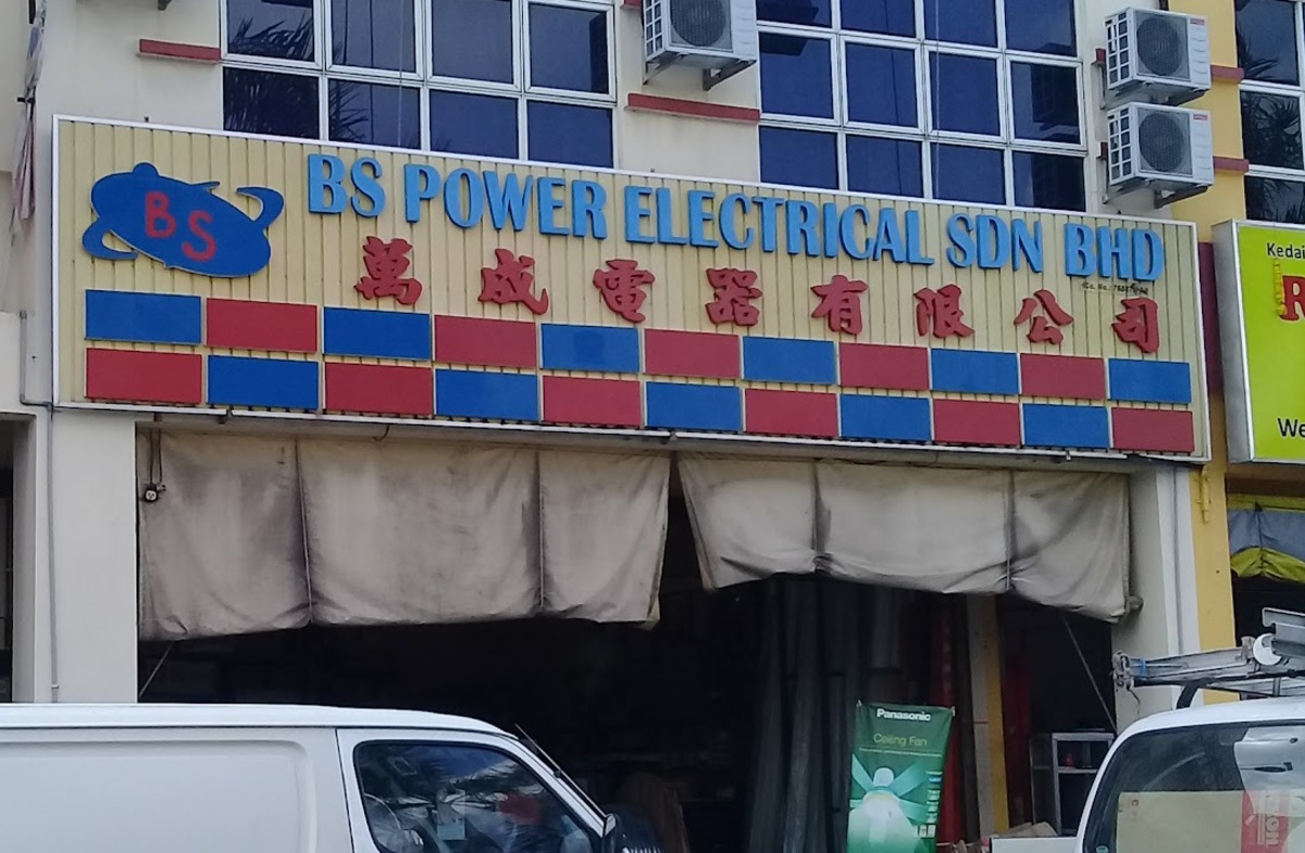 Shop signboard reading BS Power Electrical Sdn Bhd with Chinese characters and red and blue panels, above an open shopfront with canvas blinds